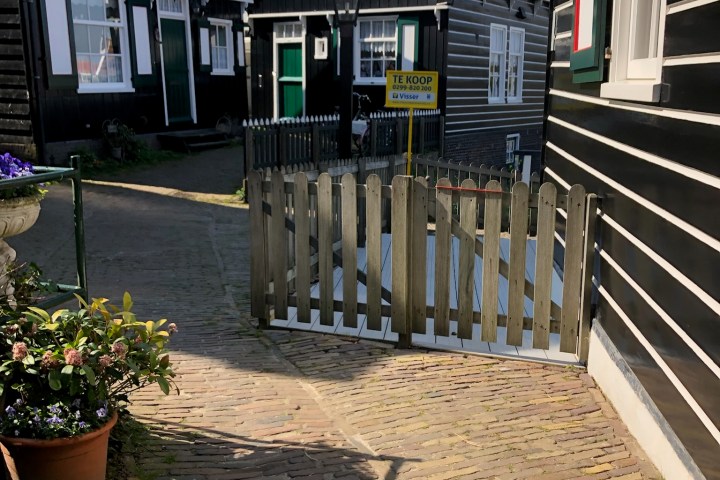a house with a fence in front of a brick building
