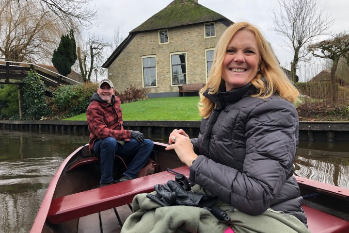 a woman sitting on a bench next to a lake