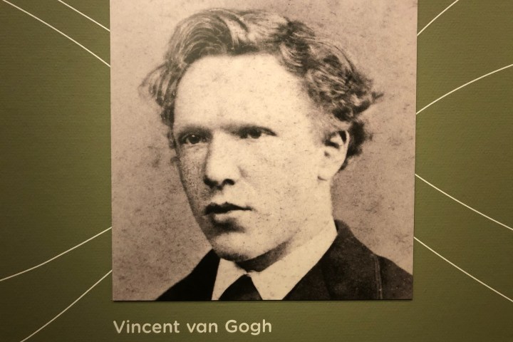 Sepia-toned portrait of a man with wavy hair and suit on green background.