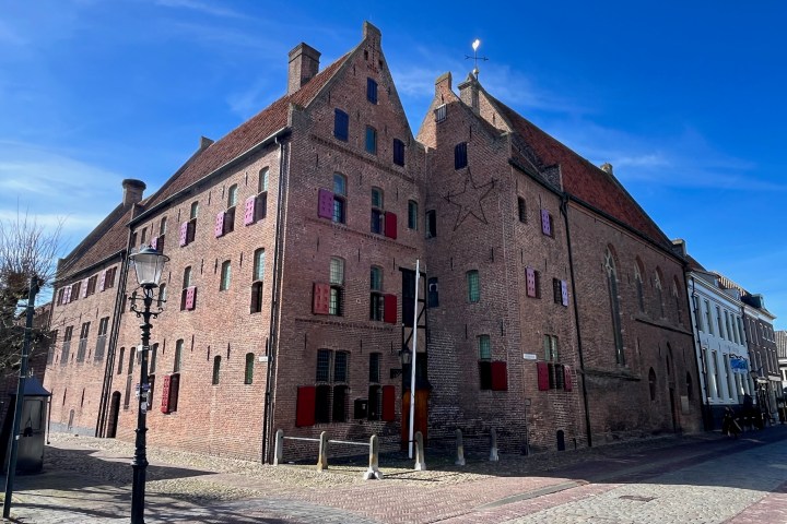 Historic brick building with colorful shutters under a clear blue sky.