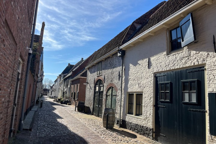 Narrow cobblestone street with old brick buildings under a clear blue sky.