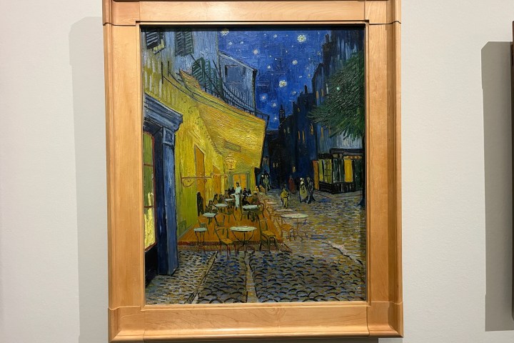 Framed painting of a brightly-lit outdoor café at night with stars.