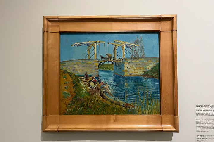 Framed painting of a bridge over a canal with people and a boat.